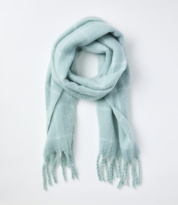 A light blue fringed scarf is laid out on a plain white background.