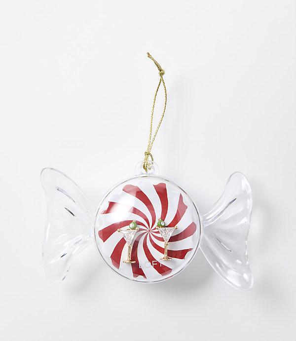 A candy-shaped Christmas ornament with red and white swirls and two martini glasses sits against a plain white background.