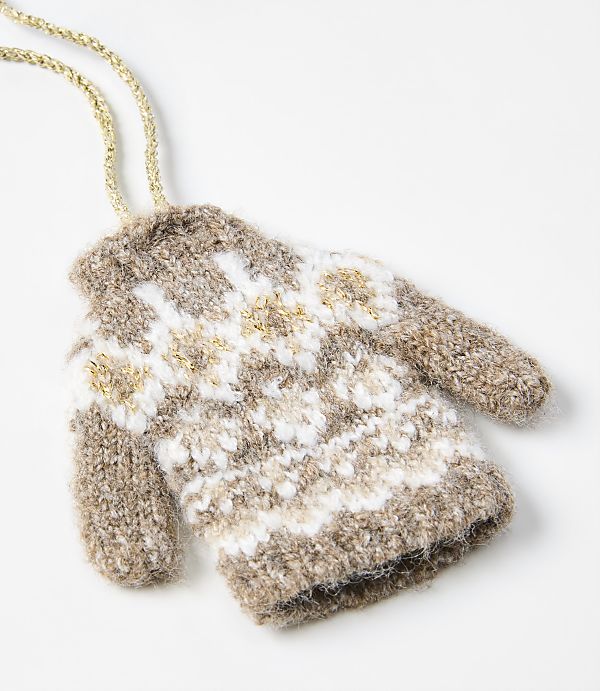 A brown and white patterned knit mitten with a gold string lies on a plain white background.