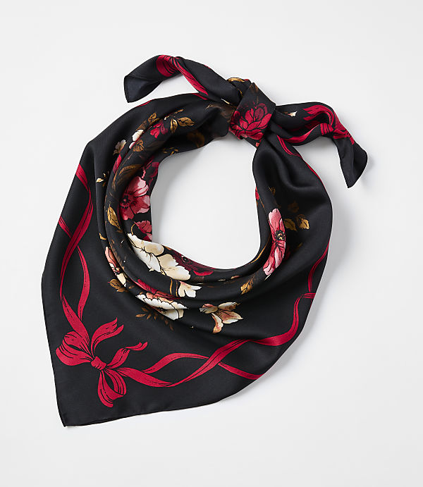 A black floral scarf with red and white blossoms is tied in a knot against a plain white background.