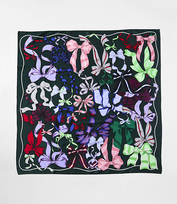 A variety of colorful ribbons and bows are scattered across a dark green fabric background.