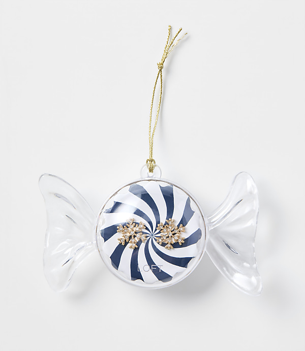 A candy-shaped Christmas ornament with blue and white stripes and gold snowflakes hangs by a gold string against a plain white background.