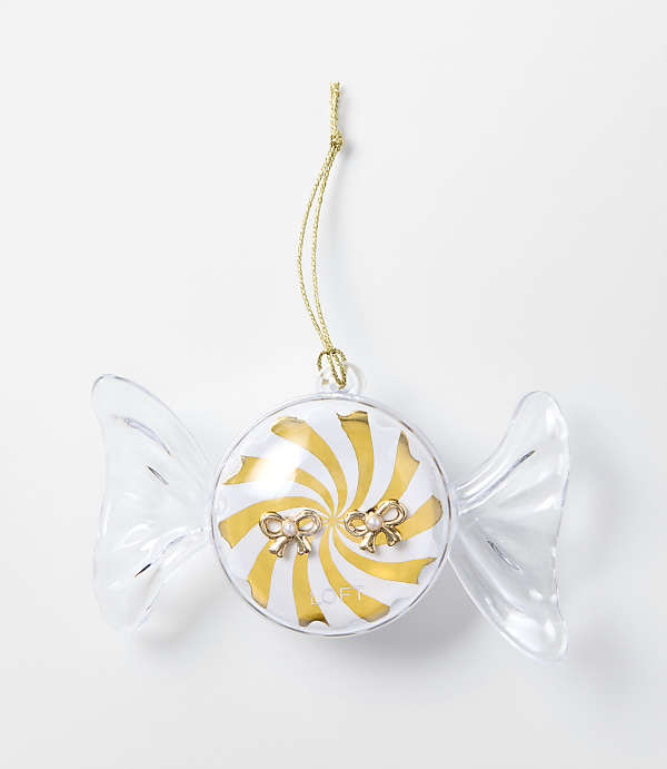 A clear, candy-shaped ornament with a gold and white swirl center and small bows sits against a plain white background.