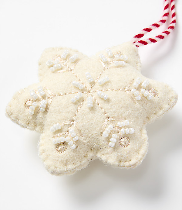 A white felt snowflake ornament with pearl bead embroidery and a red-and-white string sits against a plain white background.