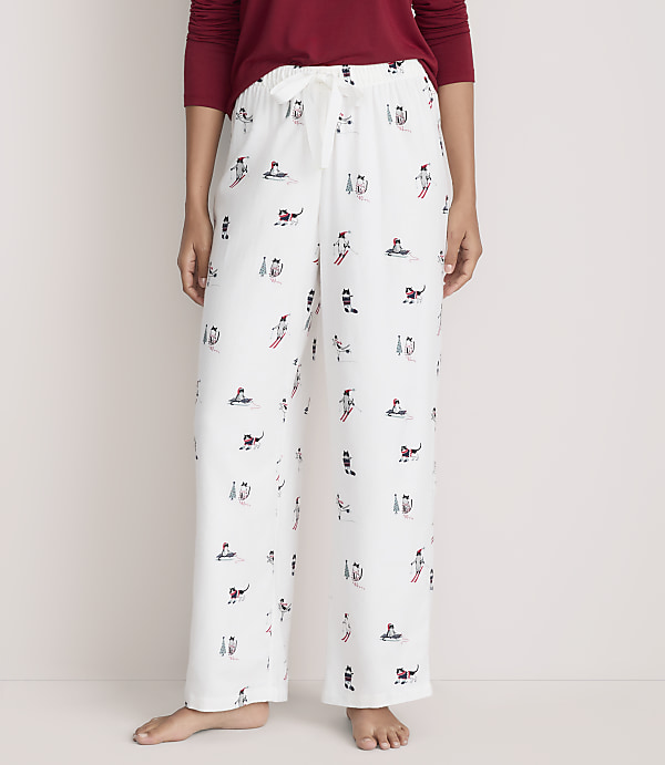 A person wearing a red shirt and white patterned pajama pants stands against a plain, light-colored background.