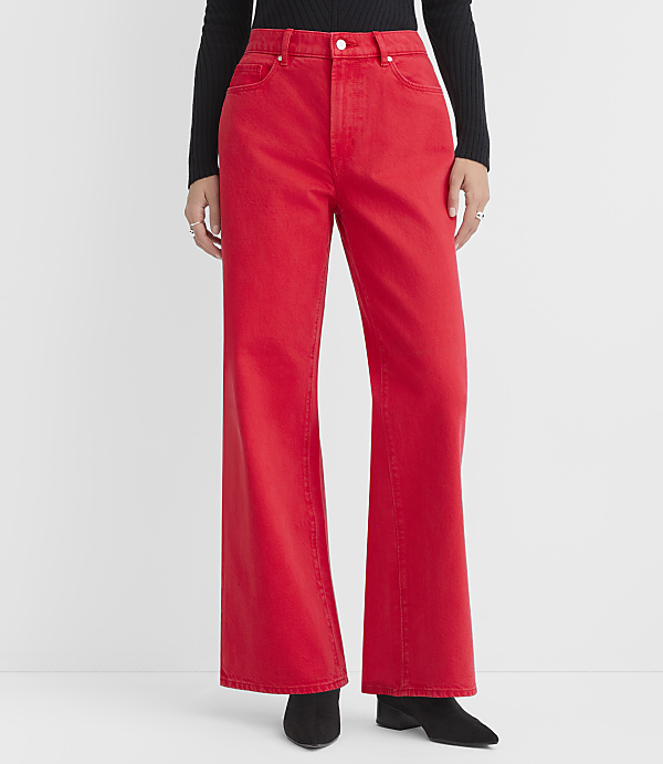 A person stands in the foreground wearing bright red flared jeans and black boots against a plain white background.