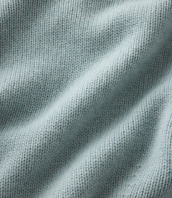 Light blue knitted fabric with soft folds fills the entire foreground and background.