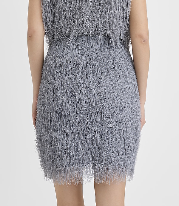 A person is seen from behind wearing a grey shaggy faux-fur dress against a plain white background.