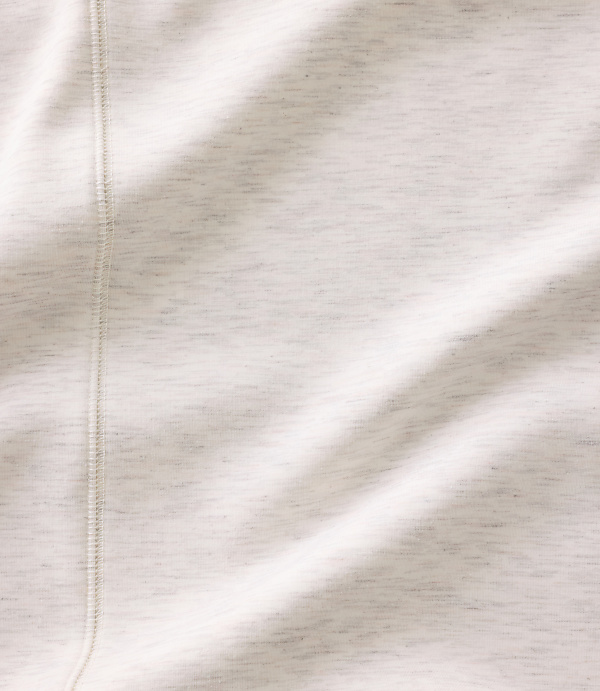 A close-up of a white fabric with a vertical seam in the foreground and soft folds across the background.