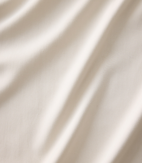 Soft, cream-colored fabric with gentle folds in the foreground and a smooth, blurred backdrop.