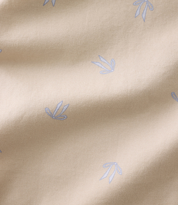 Small, light blue floral patterns are scattered across a draped, beige fabric background.