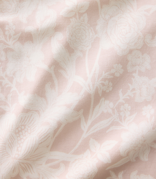 White floral patterns are printed across a draped, light pink fabric background.