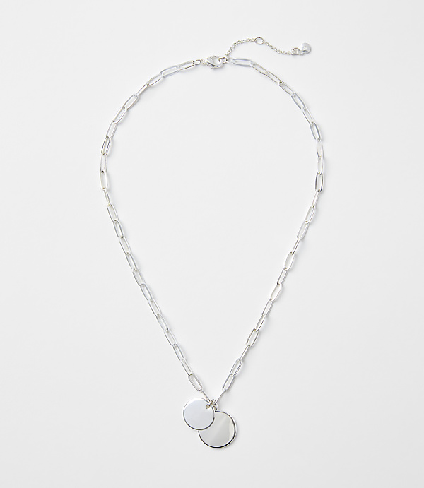 A silver chain necklace with two circular pendants rests on a plain white background.