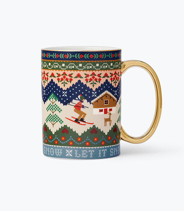 A white mug with a gold handle features a winter-themed illustration of a skier and a cabin against a plain white background.