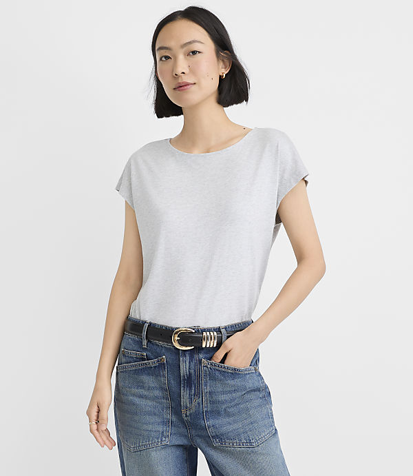 A woman in a grey t-shirt and a patterned denim skirt stands against a plain white background.