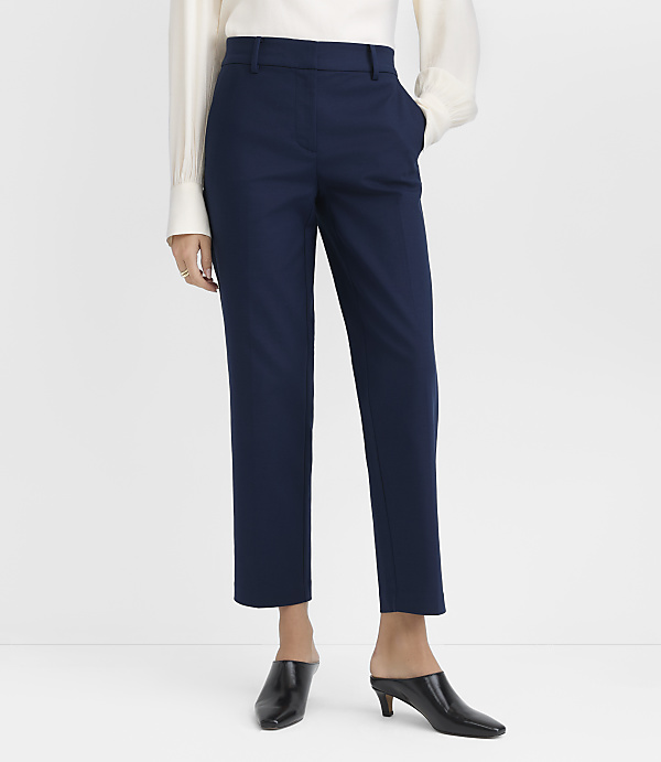 A person wearing navy blue cropped pants and black heeled sandals stands against a plain white background.